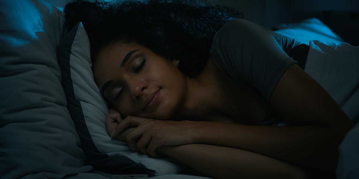 Woman sleeping comfortably in bed at night, demonstrating restful sleep achieved by managing peripheral neuropathy pain with effective evening remedies.